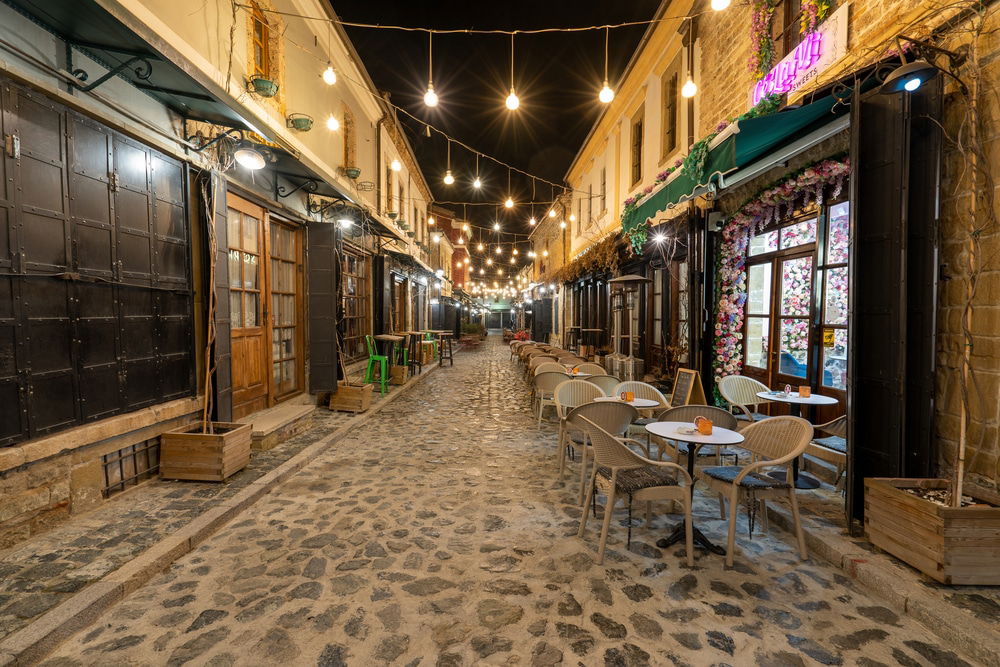 Old Bazaar - City Guide: Discover the charm of Korçë, Albania's "Albanian Little Paris," as you stroll down a cobblestone street lined with cozy tables and chairs.